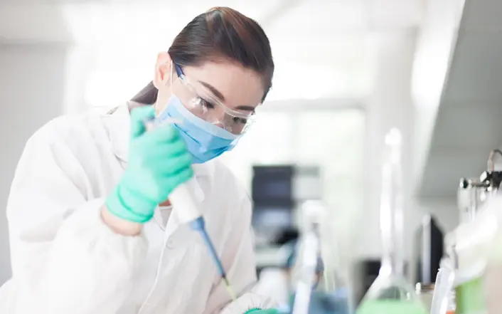 A scientist in a laboratory conducting research with a pipette.
